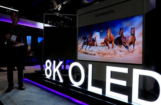 今年1月9日，在美国拉斯维加斯，一名工作人员站在创维8K OLED电视前。（新华社）