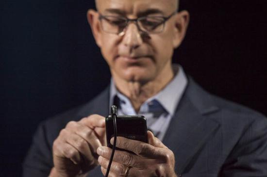 资料图：亚马逊公司首席执行官杰夫·贝索斯展示亚马逊发布的第一款智能手机“Fire Phone”。 （新华社）