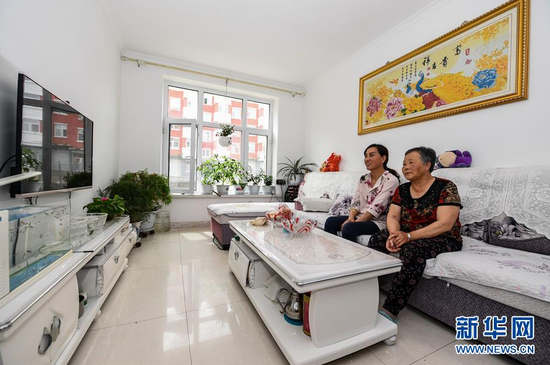 苏艳梅（后）和婆婆李秀珍在阿尔山市伊尔施街道伊林小区新居中看电视（8月11日摄）。新华社记者 刘磊 摄