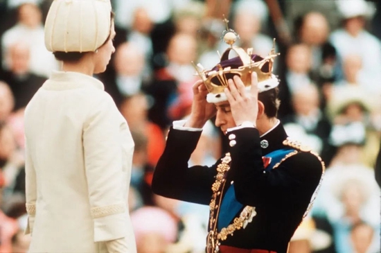 1969年7月1日，英国威尔士，卡那封城堡，女王伊丽莎白二世为受封的查尔斯王子戴上威尔士亲王的金色冠冕。（图丨视觉中国）