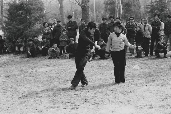 1981年，穿喇叭裤、自带双卡收录机的西安青年在公共场所跳迪斯科，引来人们围观。摄影|胡武功