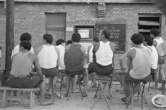 1985年，陕西西安纺织城家属区，看公共电视的居民。摄影|胡武功