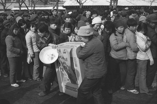 1989年，陕西澄城县，买奖券中奖后抬着奖品的农民。摄影|胡武功