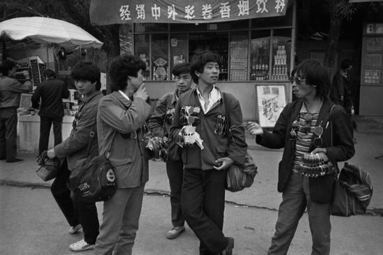 1985年，北京街头出没的流动小商贩，正向行人兜售“蛤蟆镜”。摄影|郭建设