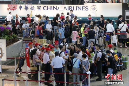 资料图：台湾桃园机场内，中华航空公司服务台前的旅客排起长队。中新社记者 陈小愿 摄