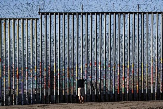 ▲在墨西哥边境城市蒂华纳，一名男子在美墨边境墙边停留。（新华社）