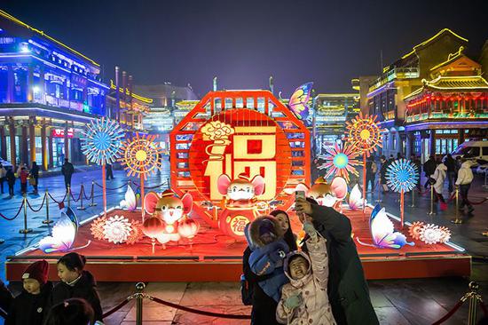 游客在鼠年元素花灯前拍照。