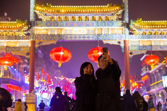 游客在正阳门牌楼前拍照。