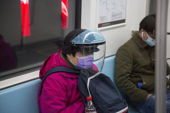 2020年2月10日，地铁里有乘客戴着面罩，做好更全面的个人防护。下班前后，地铁里乘客较之前多了不少，基本每排座位上都有人，但大家谨慎地保持着距离，有的人更愿意站着。 澎湃新闻记者 史阳琨 图