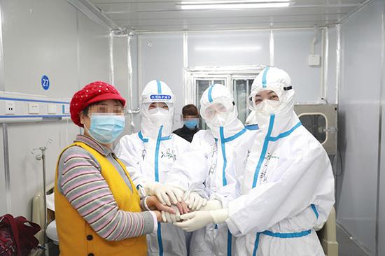 2月16日，在武汉雷神山医院病房，新入院患者与医护人员相互鼓劲加油。 新华社 图