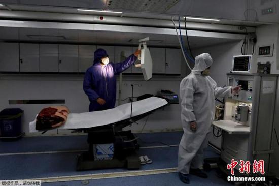 当地时间3月26日,伊朗德黑兰国际展览中心,穿防护服的工作人员在操作医疗设备。