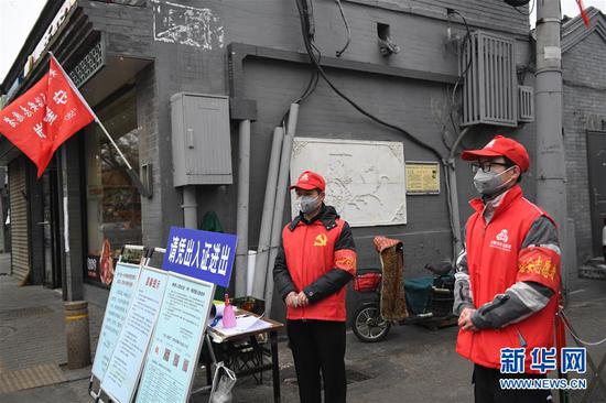 2月27日，志愿者张建国（左）和儿子张洪赫在北京市东城区安定门街道花园社区车辇店胡同口的疫情防控值班点值守。  新华社记者 鞠焕宗 摄