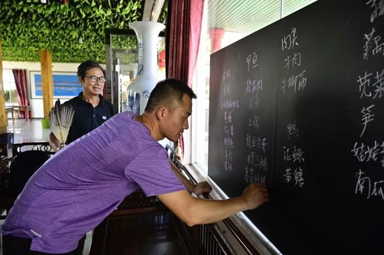 2020年 6月16日，在江西省余干县田园鄱阳湖景区，上岸渔民朱义才（左）在自己开办的农家乐内和儿子一起写当日的菜谱。（新华社记者 彭昭之 摄）