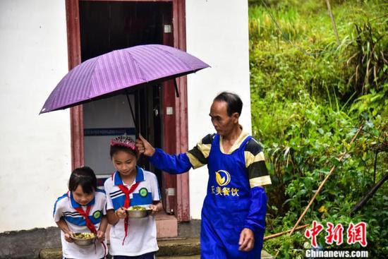 下雨时，周宏军为学生撑起伞。