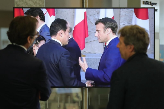 3月24日，在比利时布鲁塞尔的北约总部，人们观看屏幕上日本首相岸田文雄、法国总统马克龙出席七国集团峰会合影仪式的画面。新华社记者郑焕松摄