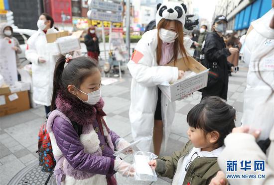 2月29日，在日本东京池袋站前，一名小志愿者（左）向当地小朋友发放儿童用口罩。当日，由在日华侨华人发起的志愿者团体“口罩熊猫行动小组”在日本东京池袋站前向当地民众免费发放口罩，感谢日本各界在中国遭遇新冠肺炎疫情时对中国提供的无私帮助。新华社记者 杜潇逸 摄