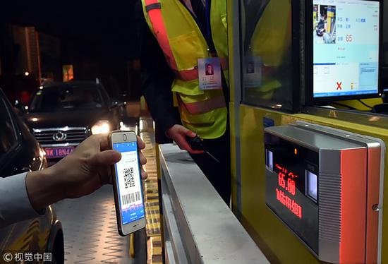 10月23日,江苏扬州,一位司机在收费站出口用手机扫码付费.