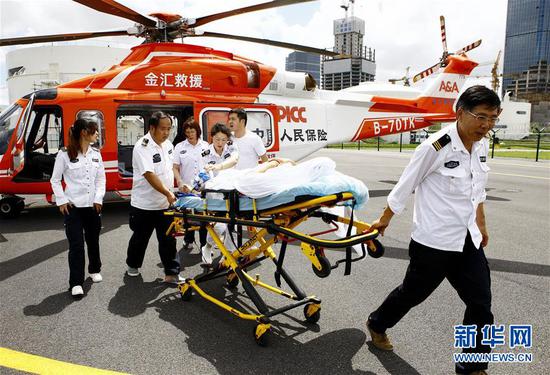 8月27日，江苏泰兴市人民医院一位脑出血危重病患，经由直升机救援转运，仅用时1小时20分钟飞抵上海，再由地面救护车快速送抵上海瑞金医院接受进一步抢救治疗。这是上海120急救人员与同机抵达的泰兴市人民医院医护人员一起将病患转运至救护车。 新华社记者 方喆 摄