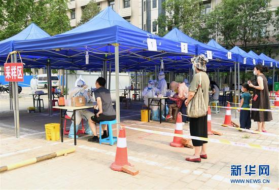 6月23日，在北京市海淀区八里庄街道的一处核酸检测采样点，八里庄街道居民在进行咽拭子采样。新华社记者 任超 摄