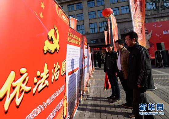 西安市民在国家宪法日宣传活动现场观看依法治国宣传展板（2014年12月4日摄）。新华社记者 李一博 摄