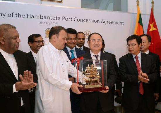 在汉班托塔港运营协议签署仪式上，斯里兰卡港口运输部部长马欣达·萨马拉辛哈和中国招商局港口控股有限公司副主席胡建华交换礼物。
