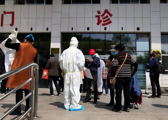 ▲4月6日，进入中南医院门诊楼前，患者要扫码登记个人信息。新京报记者王双兴摄