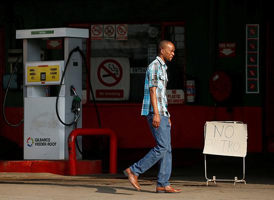 行人经过津巴布韦哈拉雷一个加油站。视觉中国 资料