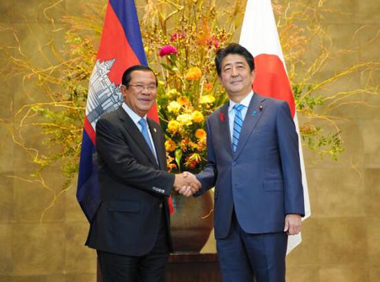 安倍与柬埔寨首相洪森握手(图片来源:日本《朝日新闻》)