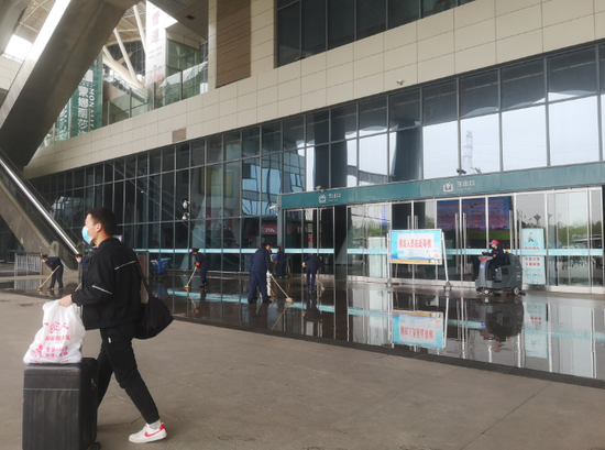 ▲4月5日，武汉站内的工作人员正在用水冲洗地面。新京报记者 李桂 摄