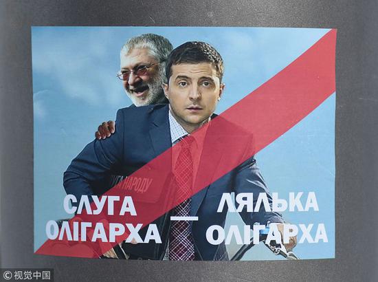乌克兰利沃夫街头的一张改自《人民公仆》海报的传单，图正中为泽连斯基，而他身后则是科洛莫伊斯基，文本大意为“寡头之仆，寡头傀儡”。（视觉中国）