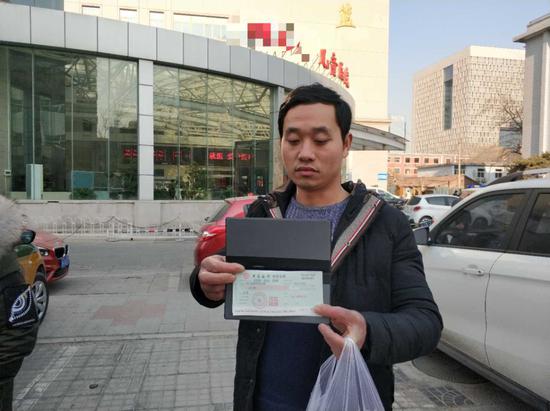孩子爸爸在医院门口接受9958救助中心送来的治疗款（支票）。新京报记者 王洪春 摄