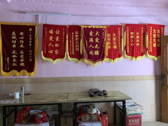 易雄住的出租屋里，挂满了流浪者家属送的锦旗。新京报记者周小琪 摄