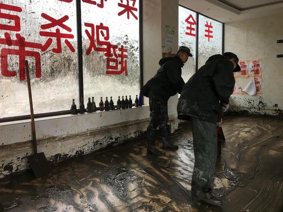 8月22日,两位武警在帮助清理村民所经营饭店中的淤泥。 新京报记者 周世玲 摄