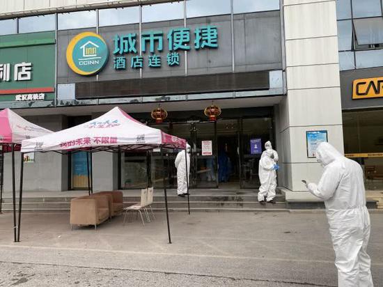 工作人员在隔离酒店门口，等待解除隔离的居民