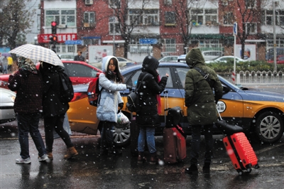 昨日上午9时许，大雪如鹅毛，南三里屯路几位路人等待出租车。新京报记者 薛珺 摄