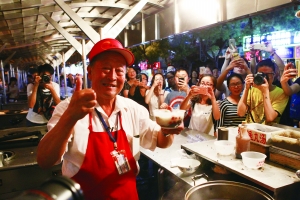 昨夜是东华门夜市营业的最后一晚。待收摊后，东城城管委在街两端设立警示灯，施工单位进场设立围挡，启动道路改造工程。图为卖了32年鱼丸的滕老爷子昨晚卖完最后一碗，和老食客告别。北京晨报记者 王颖/摄