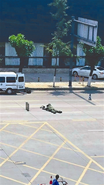 身着拆弹制服的人员趴在马路上，处理前方的可疑装置 图由网友提供