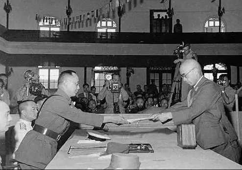 日军最高指挥官冈村宁次(右)在南京向中国陆军总司令何应钦递交投降书