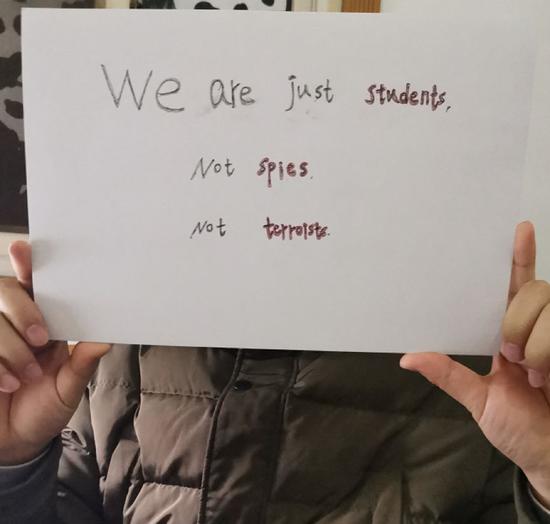 （图为维权学生举着“我们只是学生，不是间谍，不是恐怖分子”的标语）
