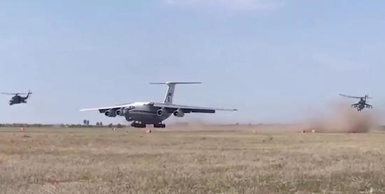 ▲伊尔-76MD在降落过程中，2架米-24武直在旁边进行空中掩护，场面酷似战争片。（“今日俄罗斯”电视台视频截图）
