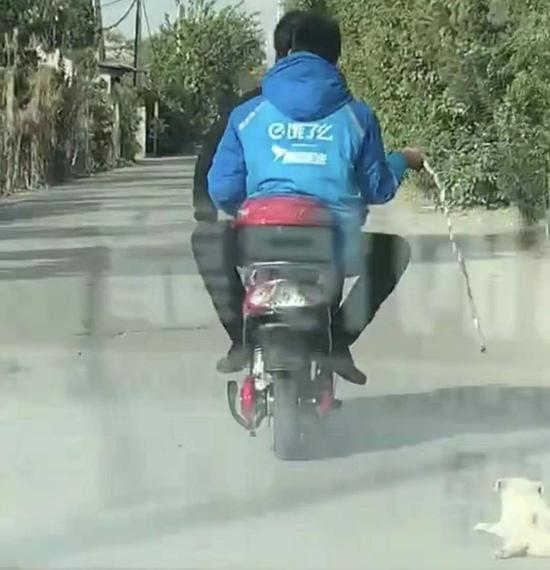 穿“饿了么”工作服的男子在拖行小狗。    行车记录仪视频截图