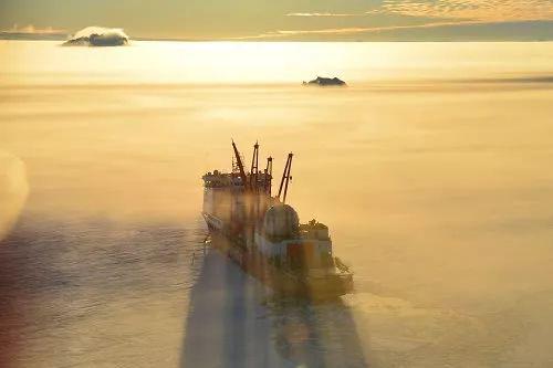 ▲这是完成中山站卸货任务的直升机机长杨佃良驾驶直升机返航时拍摄的在雾气缭绕的南极海冰中的“雪龙”船。