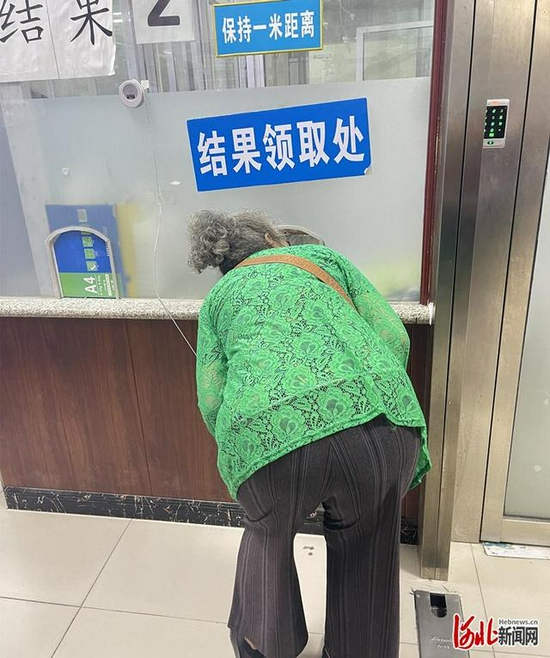 图为一名老人“卑躬屈膝”在窗口前领取化验结果。 网民杨女士供图