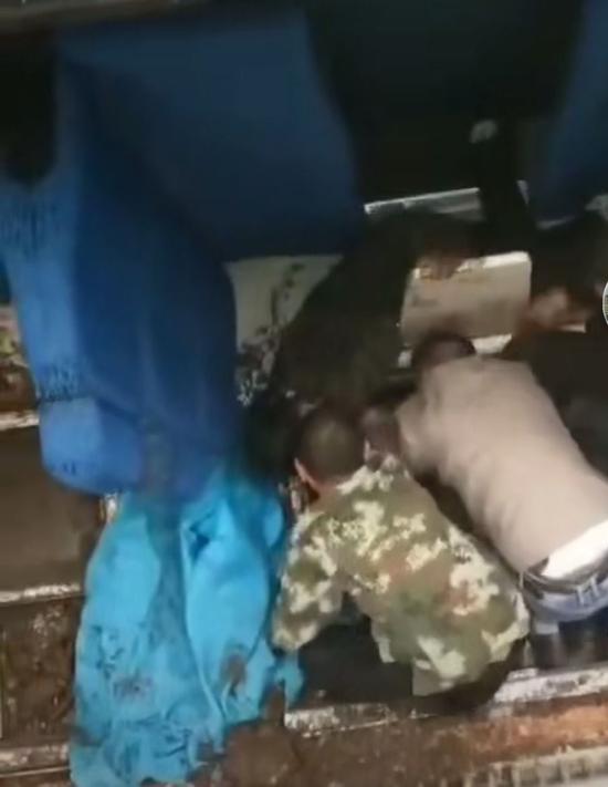 有人员从车窗内下到车厢内部救援被压受伤人员。视频截图