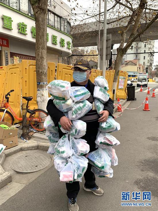 在武汉市江岸区黄石路汉口大药房，惠民苑社区网格员丰枫把为居民购买的药挂在身上（2月24日摄）。 新华社发