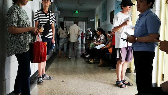 北京中医药大学东方医院二层，患者等候就诊。因为座位不足，不少患者只能站着等待。 摄影/新京报记者 侯少卿