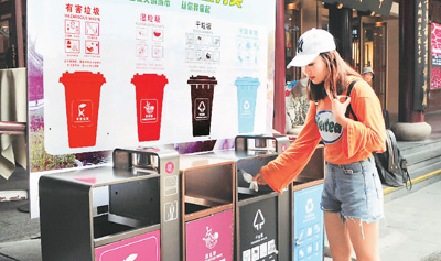 五月十二日,游客在上海市豫园商城中心广场垃圾分类箱前投放垃圾。杨建正摄(人民图片)