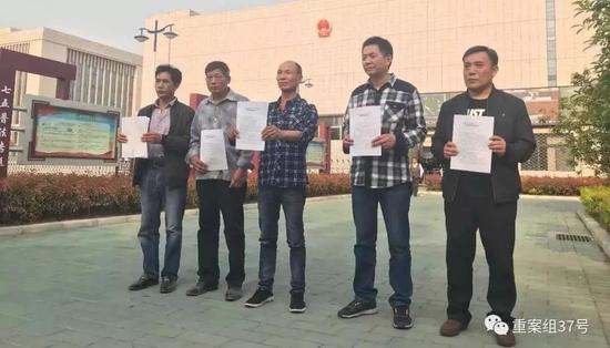 4月11日下午,周继坤等5人拿着无罪的判决书在安徽省高院前合影。