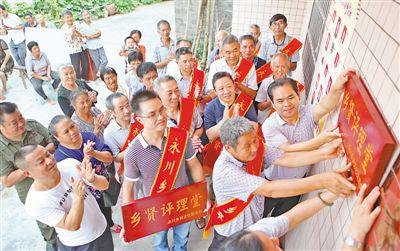 永川区永荣镇白云寺村乡贤评理员王章学（右一），在自家墙上悬挂“乡贤评理堂”牌匾。
　　陈仕川摄