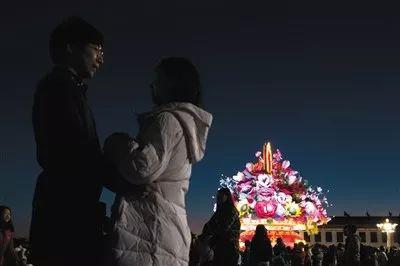 晨光微曦中对视的情侣，他们的身后是祝福祖国的花篮。新京报实习生 陈婉婷 摄